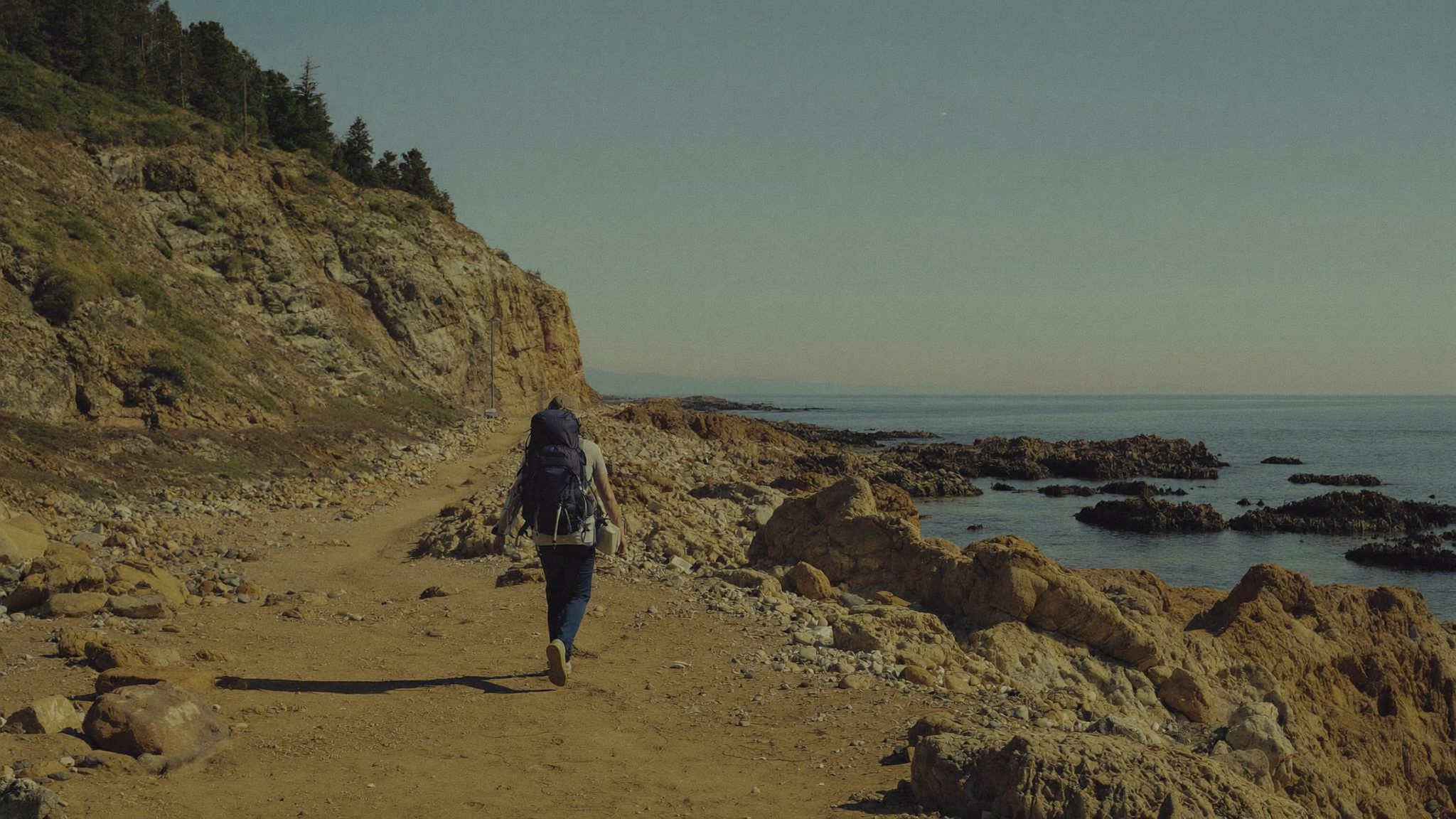 Voyageur marchant vers l'horizon sur un chemin de bord de côte